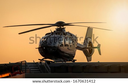 Black Helicopter tied down on platform at sunset