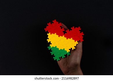 Black History Month background. African American history month celebration. Hand holding heart in red, yellow, green colors flag over black background