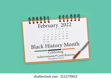 Black History Month February 2022 Calendar and pen on green background