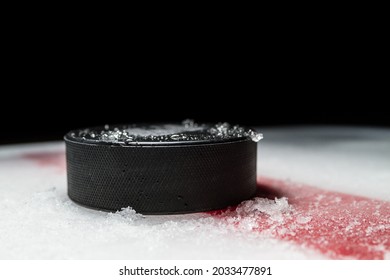 Black Hockey Puck On The Ice Rink, With Painted Red Line.