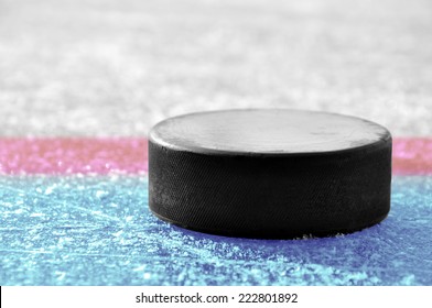 black hockey puck on ice rink 