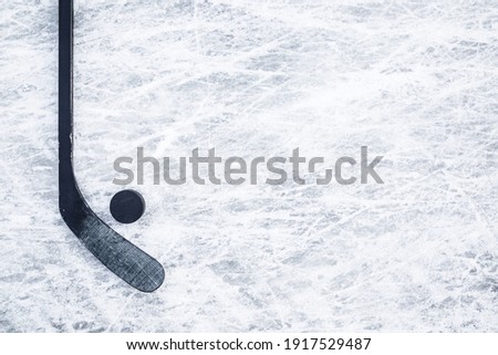 Black hockey stick and rubber puck on ice background. Closeup. Empty place for text. 