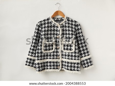 black houndstooth checked jacket on a hanger