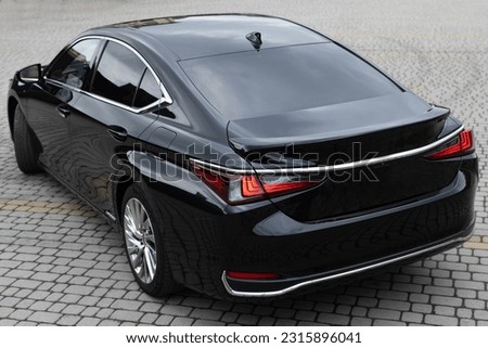 Black hybrid sedan car standing in a road. Luxury car of business class is parked on city. Back view of new black car. Black premium city sedan.