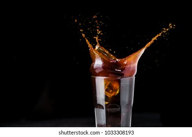 Black Iced Coffee Splash In A Glass On Black Background