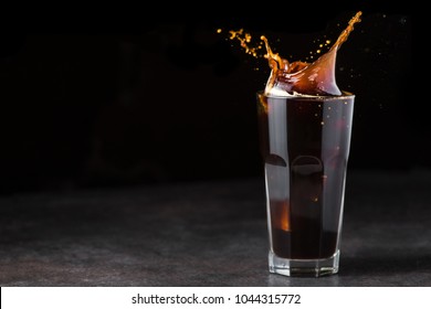 Black Iced Coffee Splash In A Glass On Black Background