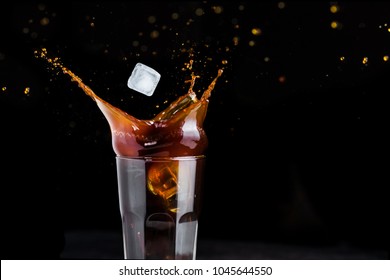 Black Iced Coffee Splash In A Glass On Black Background