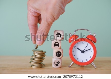 black icon, home, car, food plate and drug with red analog alarm clock, senior human's hand put coin on stack of coins , saving money for retirement concept