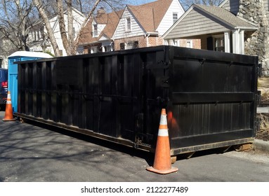 Black Industrial Dumpster Container On Neighborhood Street. 