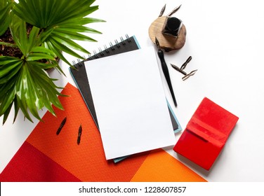 Black Ink, Ink Bottle, Green Plant, Red Book And Blank Sketchbook Page Mockup And Ink Pen On A White Background; Top View, Flat Lay; Overhead View