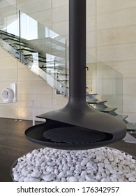 Black Iron Fireplace In The Modern Living  In The Attic Room With Wood Floor And Glass Staircase