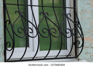 black iron grill with forged pattern on a glass window