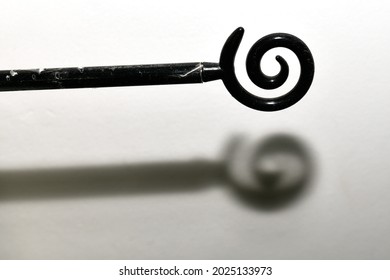 The Black Iron Rod Ends In A Spiral Shape, Made Of Iron, As A Curtain Rod And Clothesline For Beauty. White Wall Background With Shadow