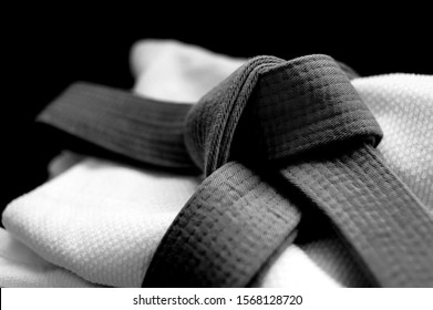 Black japanese martial art belt tied in a knot over white budo gi. Concept is applicable to sports, business or education