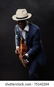 Black Jazz Musician Wearing Suit And White Hat Playing Guitar.