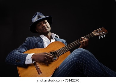 Black Jazz Musician Wearing Suit And Blue Hat Playing Guitar.