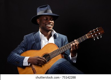 Black Jazz Musician Wearing Suit And Blue Hat Playing Guitar.