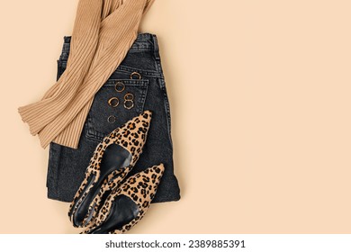 Black jeans, tank top and leopard print shoes on beige background. Fashion spring, summer or autumn outfit. Women's stylish and elegant clothes with accessory.  Flat lay, top view, overhead.