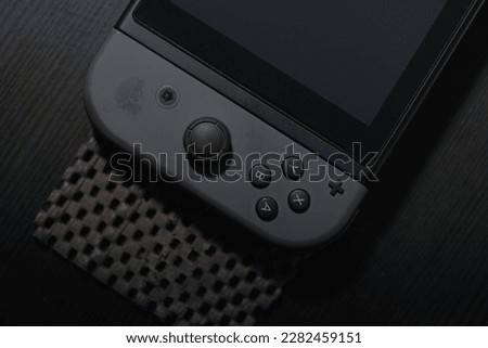black Joycon controller on a black table. Perfect for gaming enthusiasts and Nintendo fans. This photo captures the essence of entertainment and fun.