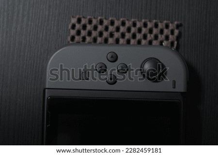 black Joycon controller on a black table. Perfect for gaming enthusiasts and Nintendo fans. This photo captures the essence of entertainment and fun.