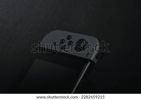 black Joycon controller on a black table. Perfect for gaming enthusiasts and Nintendo fans. This photo captures the essence of entertainment and fun.