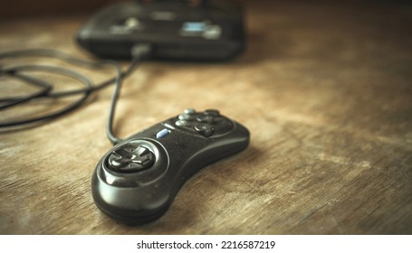 A Black Joystick From A 90's Video Game Console Is Lying On A Wooden Table. A Television Game Console Of The Last Century.