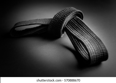 Black judo, aikido, or karate belt, tied in a knot, isolated on black background
