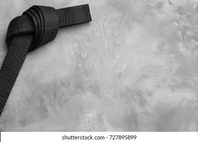 Black karate belt on grey background