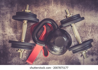 Black kettlebell and dumbbells with free weights and plates in front of it