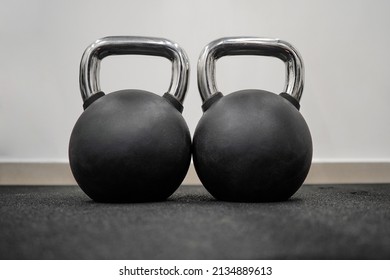 Black kettlebells in a row in a gym. Several black weights different weights. Black metal weights kettlebell one row. Sports kettlebells in sport club. Weight Training Equipment