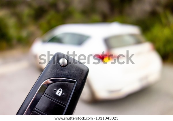 Black key fob for opening a white modern car from\
a rental company