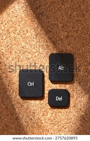 Black keyboard keys "Ctrl", "Alt", "Del" on a cork bulletin board in soft sunlight, symbolizing the classic computer reboot shortcut. Top view, flat lay.