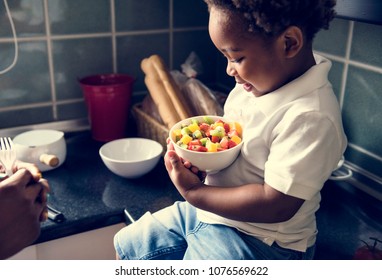 Black Kid With Fruit Salad In The Kitchen