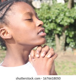 Black Kid Praying Outside With Eyes Closed 