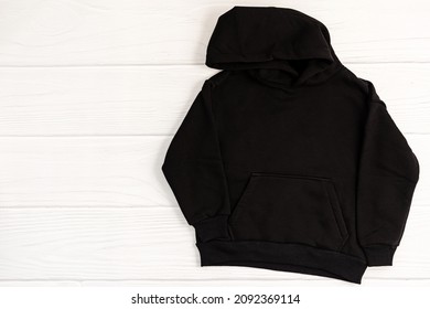 Black Kid Sweatshirt With Hood On White Background Top View. Fashionable Unisex Clothing, Hoodie, Casual Youth Style, Sports. Hoody For Design Mockup For Print. Blank Sweatshirt Mock Up