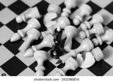 The black king stands on the chessboard, white pieces lie around him