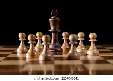 The black king surrounded by white pawns in the middle of the chessboard - Shutterstock ID 2259048641