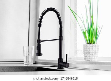 Black Kitchen Faucet On The Silver Sink Near The Glass Of Water 