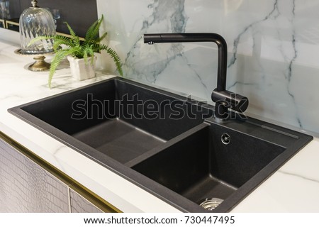 Black kitchen sink and Tap water in the kitchen. The interior of the kitchen room of the apartment. Built-In Appliances. Kitchen Appliance. Domestic Appliances