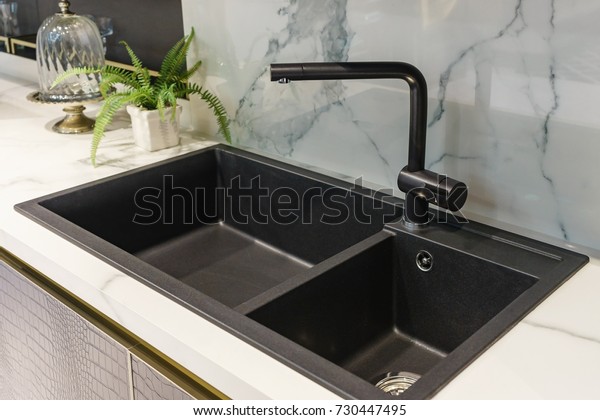 Black kitchen sink and Tap\
water in the kitchen. The interior of the kitchen room of the\
apartment. Built-In Appliances. Kitchen Appliance. Domestic\
Appliances