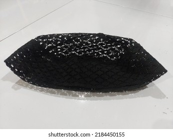 A Black Knitted Cap On A White Tile Floor At Night