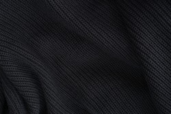 Black Knitted Fabric Texture, Warm Knitted Background. Soft Pleats And Draperies On Black Knitted Clothes