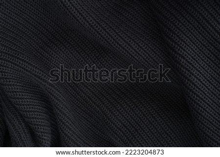 black knitted fabric texture, warm knitted background. soft pleats and draperies on black knitted clothes