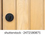 black knob with key hole made from metal stuck on wooden door. door element. copy space.