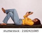 black lady lying on a bench using a phone rejoices