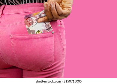 Black lady putting few Ghanaian cedi notes into her back pocket. Removing money from pocket, hold money