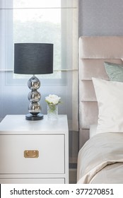 Black Lamp On White Wooden Table Side In Bedroom With Vase Of Flower