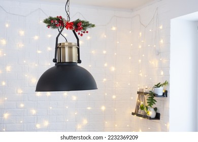 The black lampshade in the industrial loft style is decorated with spruce branches for Christmas and New Year on the background of fairy lights garlands. Close-up, minimalism - Shutterstock ID 2232369209