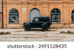 Black Land Rover Defender 90 outside historical industrial building