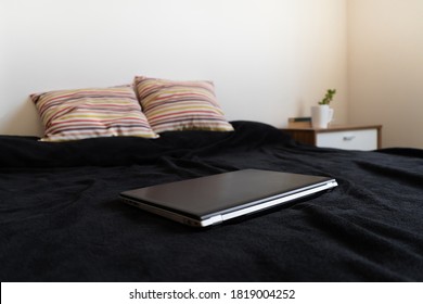 Black Laptop Closed On The Bed. Concept Of Telework And Home-office.